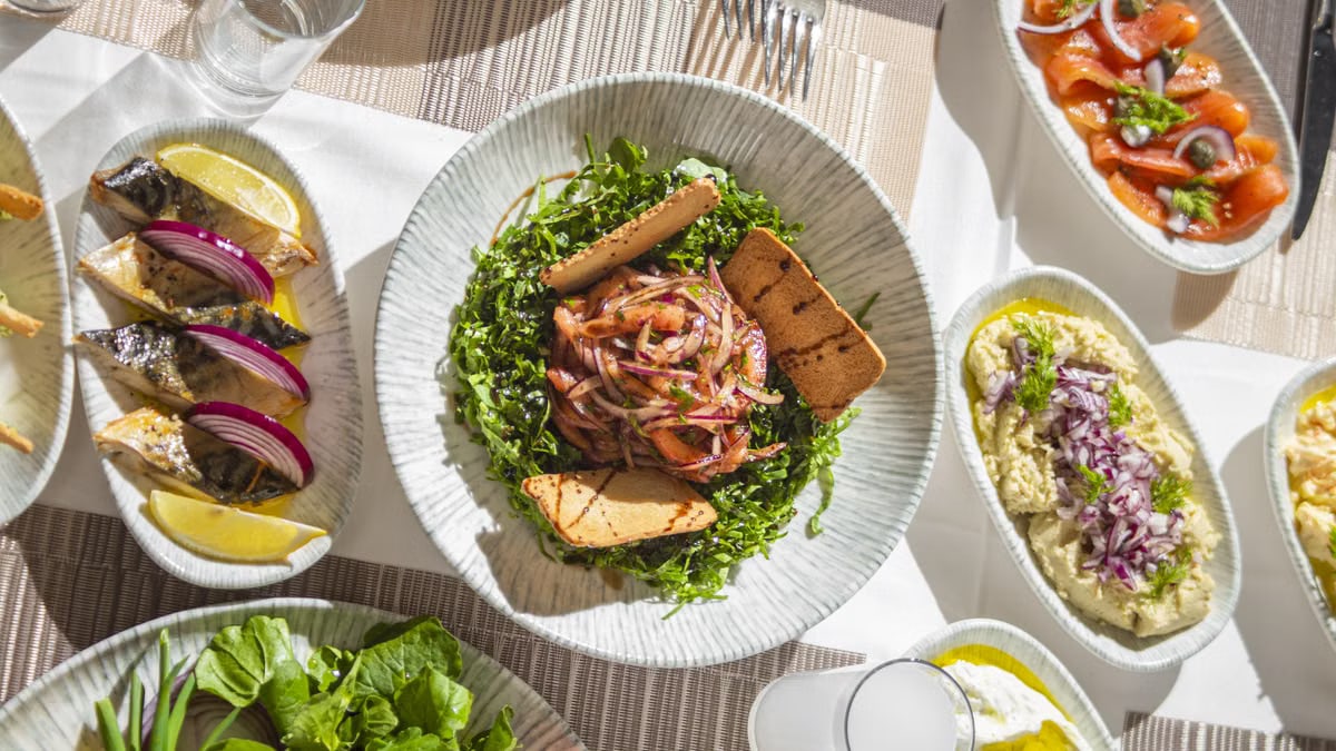 Top-down view of Mediterranean dishes including salads and seafood on an elegant table setting.